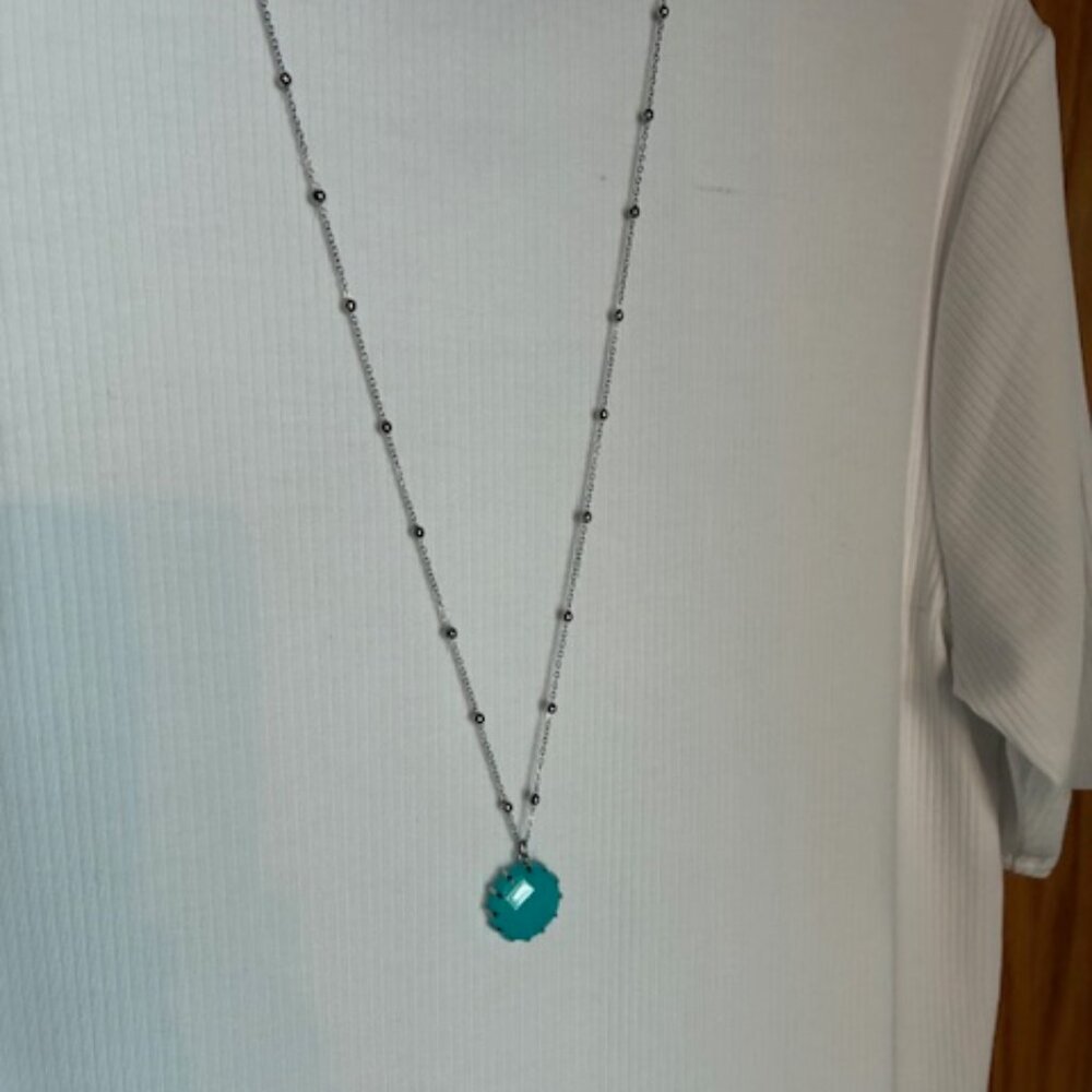 Long necklace with silver tone balls and turquoise colored stone.